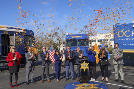 Chief probation officer and dignitaries launch confetti cannons at a press conference for new mobile resource vehicles